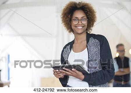 Stock Image - Portrait of smiling office worker holding digital tablet. Fotosearch