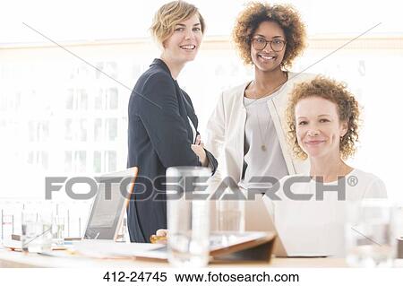 Portrait of smiling office workers sitting at desk View Large Photo Image Stock Photography - Portrait of smiling office workers sitting at desk. Fotosearch
