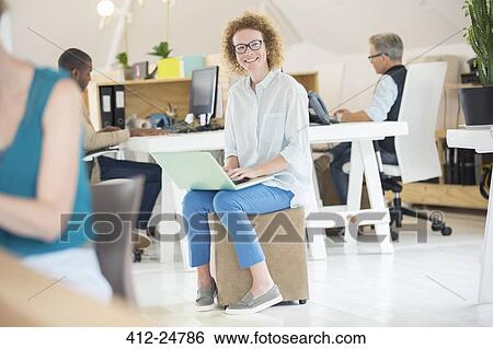 Portrait of woman holding laptop at office View Large Photo Image Stock Photograph - Portrait of woman holding laptop at office. Fotosearch