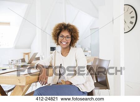 Portrait of woman sitting at desk in office and smiling View Large Photo Image Stock Image - Portrait of woman sitting at desk in office and smiling. Fotosearch