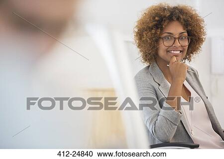 "Portrait of woman sitting in office, wearing spectacles and smiling" View Large Photo Image Stock Image - "Portrait of woman sitting in office, wearing spectacles and smiling". Fotosearch