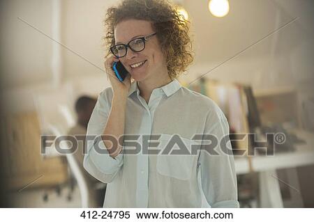 Stock Photography - Portrait of woman talking on phone at office. Fotosearch