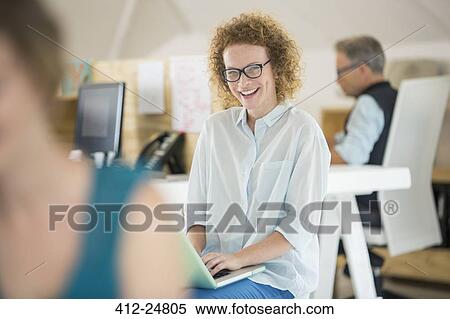 "Portrait of woman using laptop and laughing, man working in background" View Large Photo Image Stock Photography - "Portrait of woman using laptop and laughing, man working in background". Fotosearch