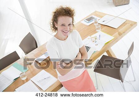 Stock Photo - "Portrait of woman with arms crossed, smiling in office". Fotosearch