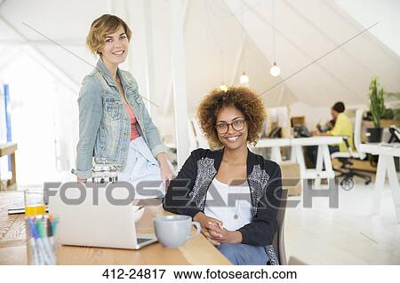 Portrait of women smiling in office with laptop on desk View Large Photo Image Stock Photo - Portrait of women smiling in office with laptop on desk. Fotosearch