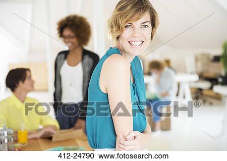 Portrait of young woman smiling at office View Large Photo Image Stock Image - Portrait of young woman smiling at office. Fotosearch