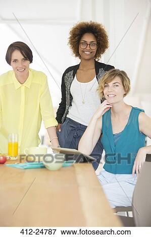 Smiling office workers talking at desk during break View Large Photo Image Stock Photo - Smiling office workers talking at desk during break. Fotosearch