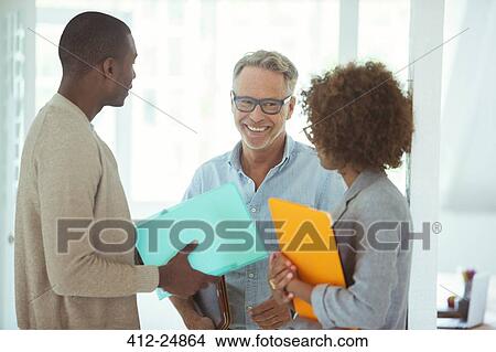 Picture - Three office workers talking at office. Fotosearch