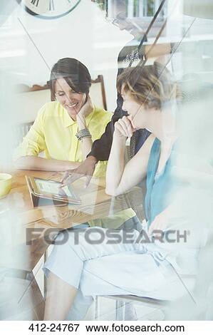 Stock Photo - Two office workers talking at desk using tablet. Fotosearch
