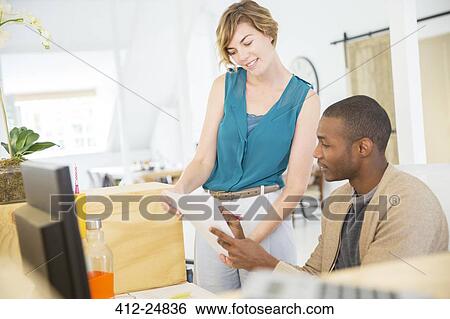 "Woman and man looking at documents, talking and smiling in office" View Large Photo Image Stock Photograph - "Woman and man looking at documents, talking and smiling in office". Fotosearch