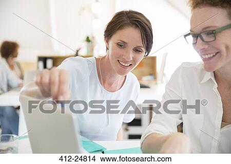 Women using laptop in office and smiling View Large Photo Image Picture - Women using laptop in office and smiling. Fotosearch