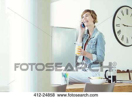 Young office worker sitting on desk at talking on phone View Large Photo Image Stock Photo - Young office worker sitting on desk at talking on phone. Fotosearch