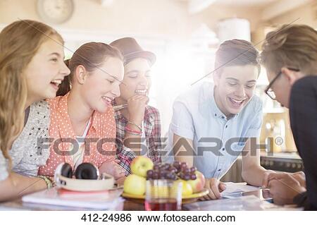 Group of smiling teenagers gathered around table in dining room View Large Photo Image Stock Photograph - Group of smiling teenagers gathered around table in dining room. Fotosearch