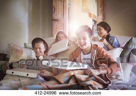 Group of teenagers opening pizza boxes on sofa in living room View Large Photo Image Stock Photograph - Group of teenagers opening pizza boxes on sofa in living room. Fotosearch