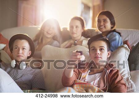 Stock Photo - Group of teenagers watching tv on sofa together. Fotosearch