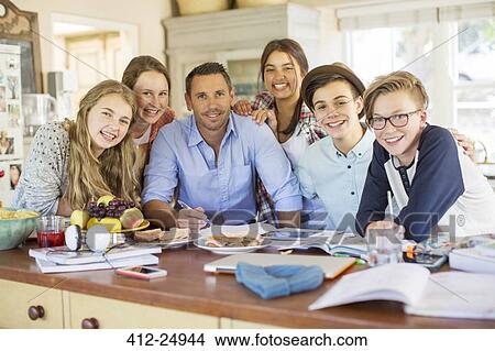 Group of teenagers with mid adult man sitting at table in dining room View Large Photo Image Picture - Group of teenagers with mid adult man sitting at table in dining room. Fotosearch