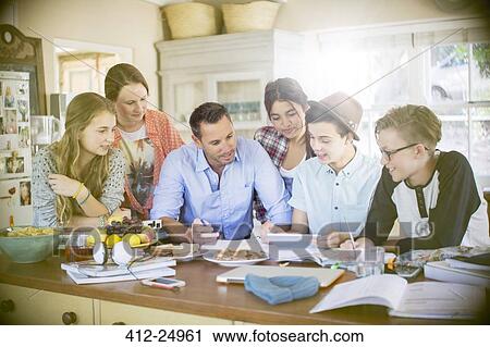 Group of teenagers with mid adult man using digital tablet at table in dining room View Large Photo Image Stock Image - Group of teenagers with mid adult man using digital tablet at table in dining room. Fotosearch