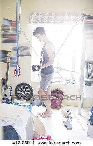 Teenage boy exercising with dumb bell in his room View Large Photo Image Stock Image - Teenage boy exercising with dumb bell in his room. Fotosearch
