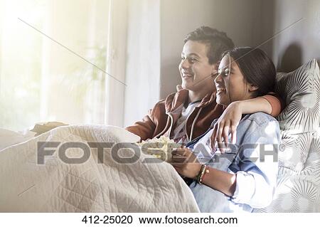Teenage couple lying in bed and watching tv View Large Photo Image Stock Image - Teenage couple lying in bed and watching tv. Fotosearch