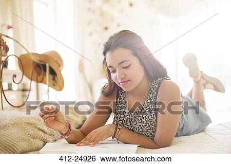 Teenage girl lying on bed and writing in notebook View Large Photo Image Stock Photograph - Teenage girl lying on bed and writing in notebook. Fotosearch