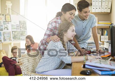 Stock Photograph - Teenagers sharing computer in living room. Fotosearch