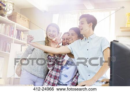 Stock Photograph - Teenagers taking selfie with digital tablet in room. Fotosearch