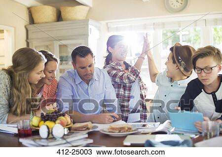 Teenagers with mid adult man sitting at table in dining room View Large Photo Image Stock Image - Teenagers with mid adult man sitting at table in dining room. Fotosearch
