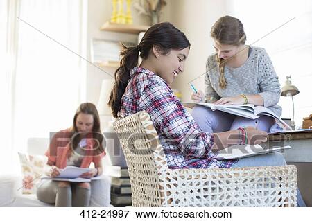 Stock Photo - Three teenage girls doing homework in room. Fotosearch