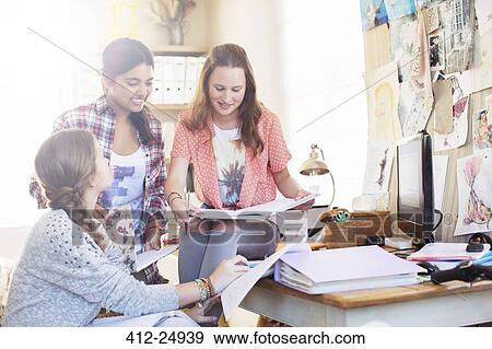 Stock Photo - Three teenage girls doing homework together in room. Fotosearch