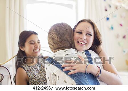 Stock Photo - Three teenage girls embracing in bedroom. Fotosearch