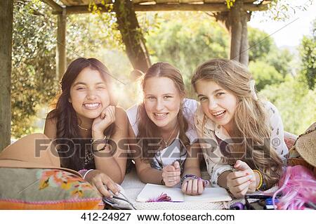 Stock Photo - Three teenage girls having fun in tree house in summer. Fotosearch