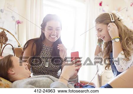 Three teenage girls listening to music on bed in bedroom View Large Photo Image Stock Image - Three teenage girls listening to music on bed in bedroom. Fotosearch