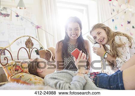 Three teenage girls listening to music from smartphone in bedroom View Large Photo Image Stock Photo - Three teenage girls listening to music from smartphone in bedroom. Fotosearch