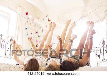 Three teenage girls lying on bed with feet up View Large Photo Image Stock Photo - Three teenage girls lying on bed with feet up. Fotosearch
