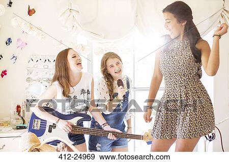 Three teenage girls playing music and singing in room View Large Photo Image Stock Photo - Three teenage girls playing music and singing in room. Fotosearch