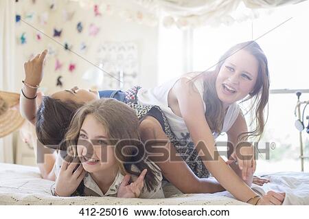 Three teenage girls playing on bed in bedroom View Large Photo Image Stock Photograph - Three teenage girls playing on bed in bedroom. Fotosearch