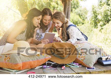 Three teenage girls using digital tablet in tree house View Large Photo Image Stock Image - Three teenage girls using digital tablet in tree house. Fotosearch