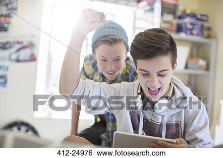 Two teenage boys having fun while using digital tablet View Large Photo Image Stock Photograph - Two teenage boys having fun while using digital tablet. Fotosearch