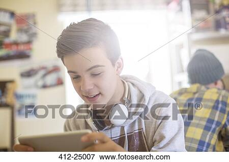 Two teenage boys sitting in room and using electronic devices View Large Photo Image Stock Photo - Two teenage boys sitting in room and using electronic devices. Fotosearch