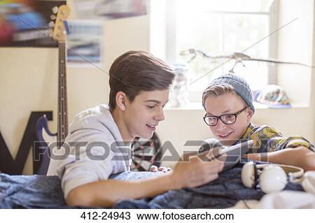 Stock Image - Two teenage sharing digital tablet in room. Fotosearch