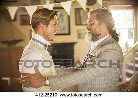 Stock Image - Best man and bridegroom standing and laughing in domestic room. Fotosearch
