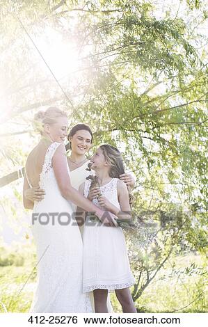 Bride and bridesmaid embracing in domestic garden during wedding reception View Large Photo Image Stock Photograph - Bride and bridesmaid embracing in domestic garden during wedding reception. Fotosearch