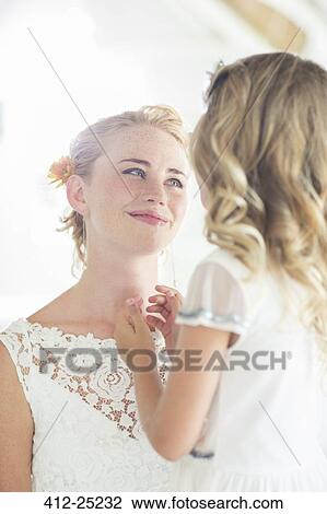 Stock Image - Bride and bridesmaid facing each other and smiling. Fotosearch