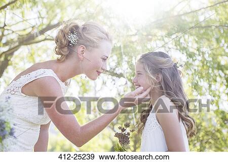 Stock Photo - Bride and bridesmaid facing each other in domestic garden during wedding reception. Fotosearch