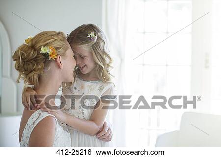 Stock Photograph - Bride and bridesmaid facing each other and smiling in bedroom. Fotosearch