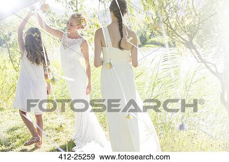 Bride and bridesmaid playing with decorations in domestic garden during wedding reception View Large Photo Image Stock Photo - Bride and bridesmaid playing with decorations in domestic garden during wedding reception. Fotosearch