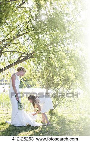 Stock Image - Bride and bridesmaid standing in domestic garden during wedding reception. Fotosearch