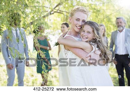 Bride embracing bridesmaid at wedding reception in domestic garden View Large Photo Image Stock Image - Bride embracing bridesmaid at wedding reception in domestic garden. Fotosearch