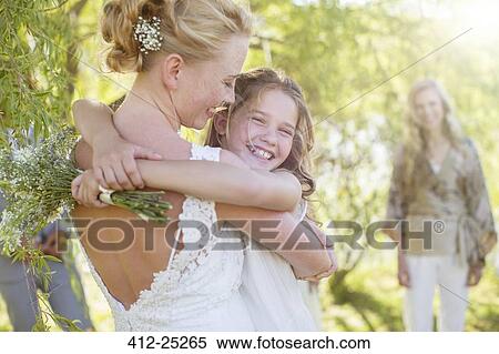 Stock Photography - Bride embracing bridesmaid at wedding reception in domestic garden. Fotosearch