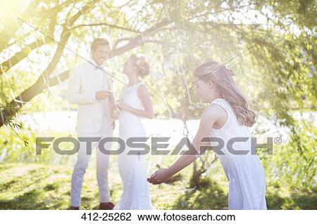 Stock Image - Bride groom and bridesmaid playing with decorations in domestic garden during wedding reception. Fotosearch